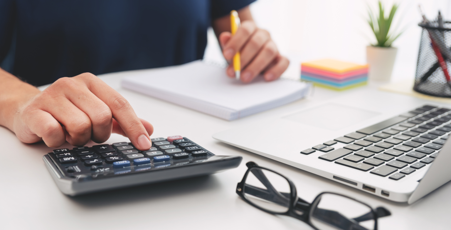 Calculadora, computadora y notas de trabajo.